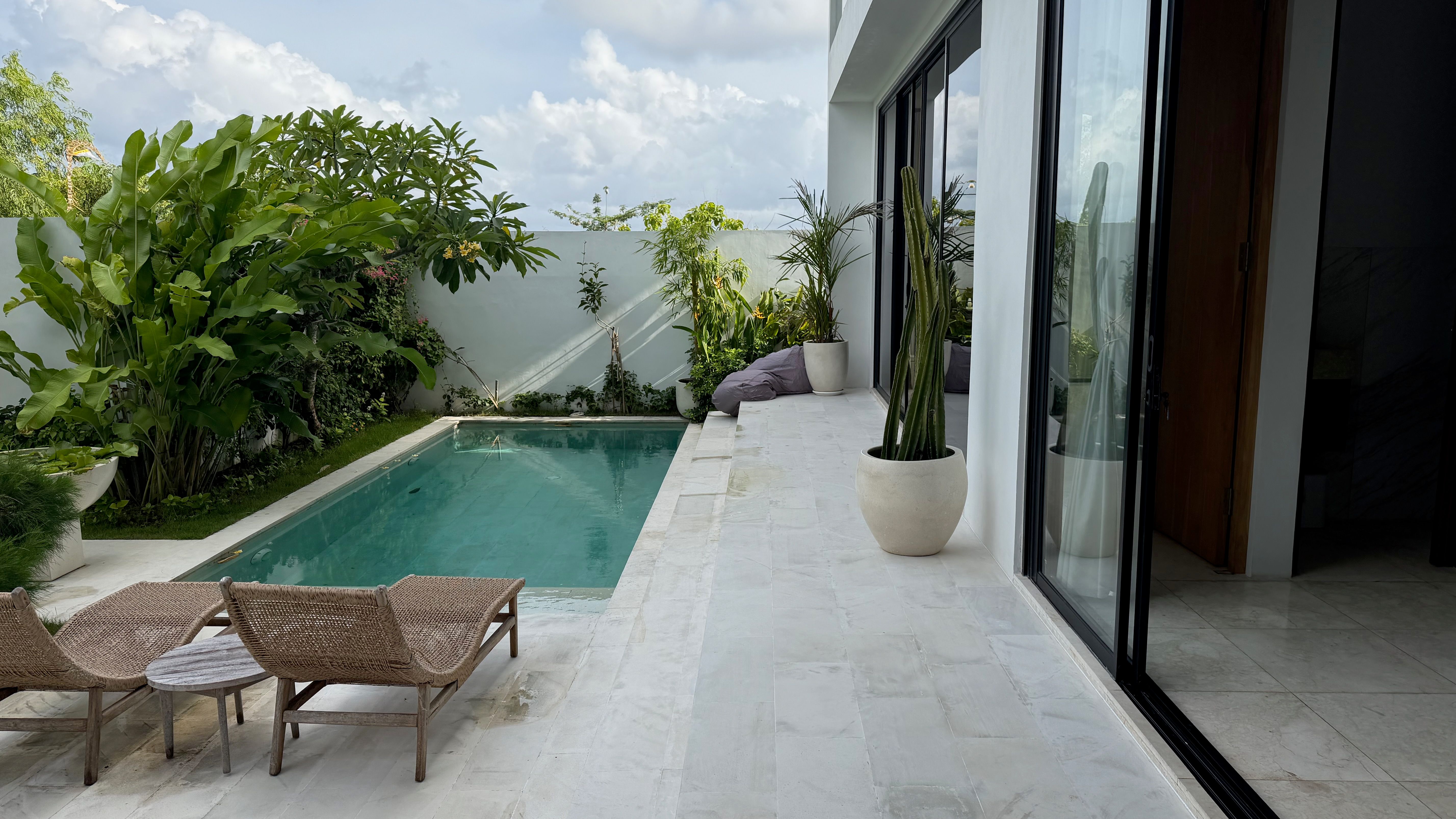 The walled plunge pool and marble deck in daylight, the white villa behind.