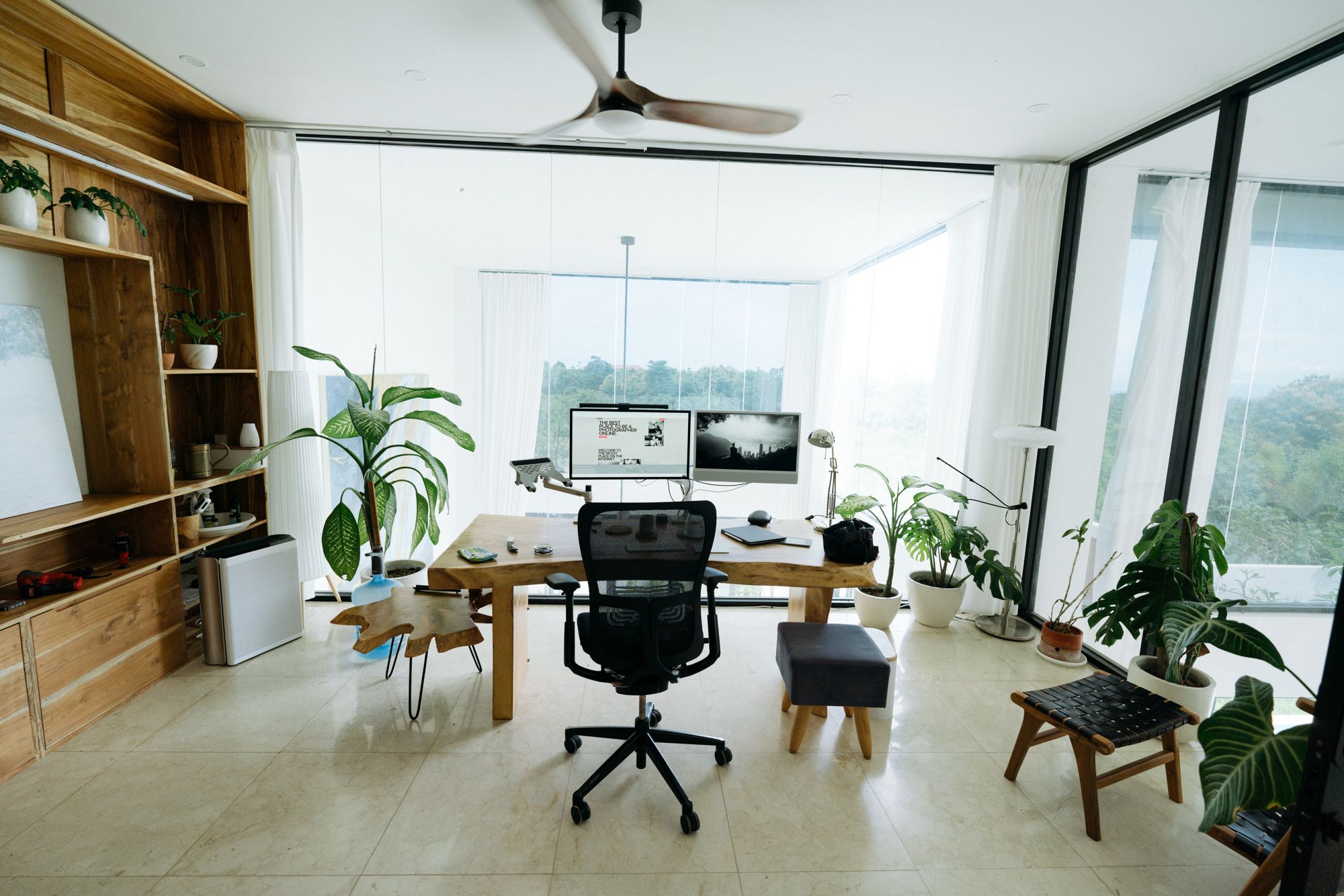 The mezzanine office: a desk, glass on two sides and the long view over the Bukit.