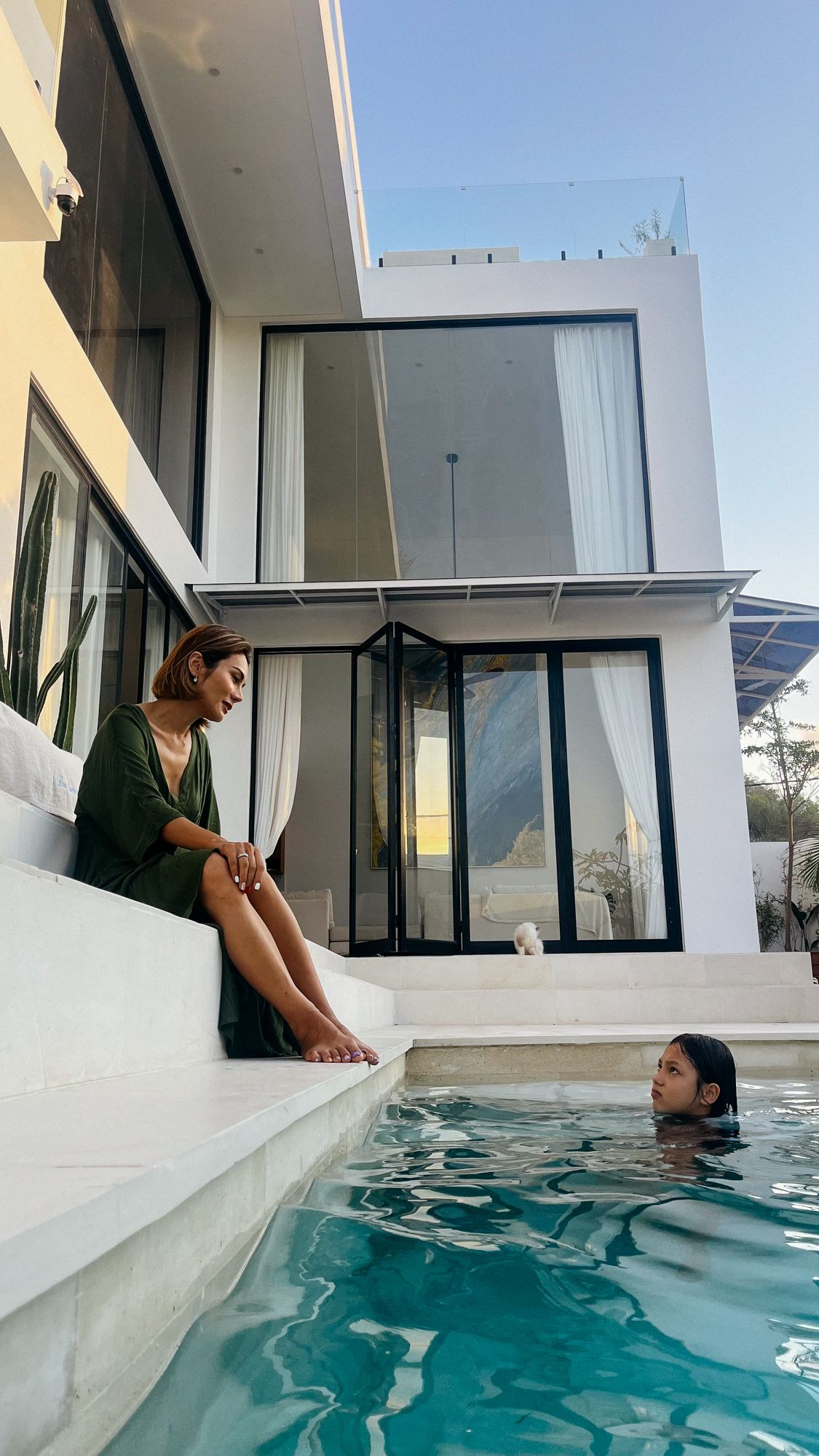 The walled plunge pool, marble steps to the water and the lit villa behind at dusk.