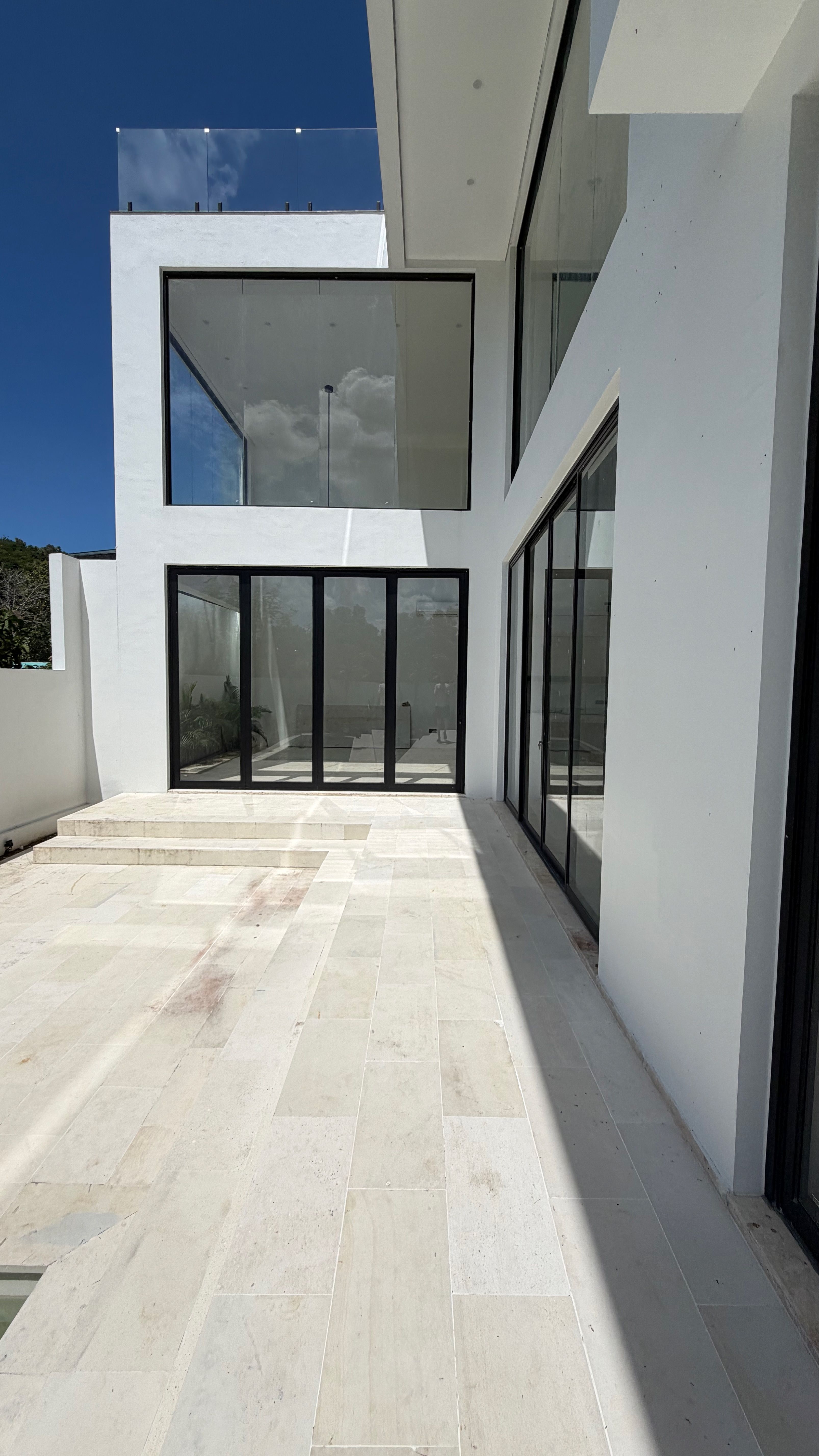 The Sunrise villa in full morning light — white render and glass around a sunlit marble courtyard.